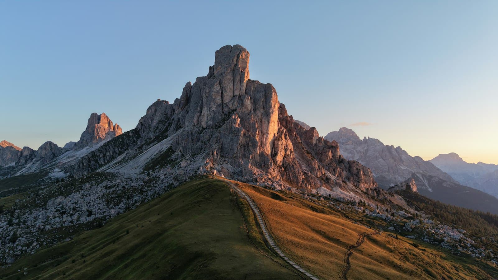 Un sendero de montaña al amanecer, serpenteando hacia la cima